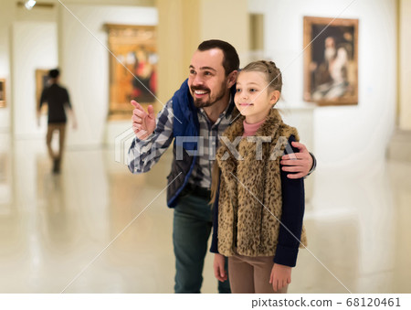 Father and daughter looking at paintings in halls of museum Father and daughter looking at paintings in halls of museum 68120461