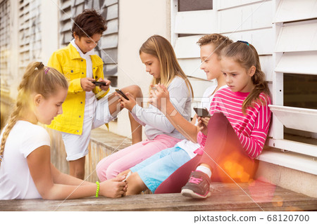 Five kidsare chatting on their smartphone Five kidsare chatting on their smartphone 68120700
