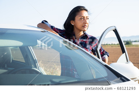 Portrait of driver latino woman next to car 68121293