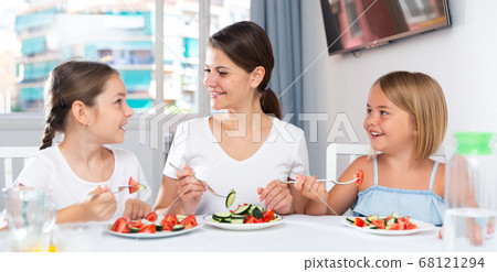 Mother and daughters eating salad in room 68121294