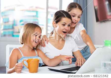 Cheerful woman and two daughters using laptop Cheerful woman and two daughters using laptop 68121342
