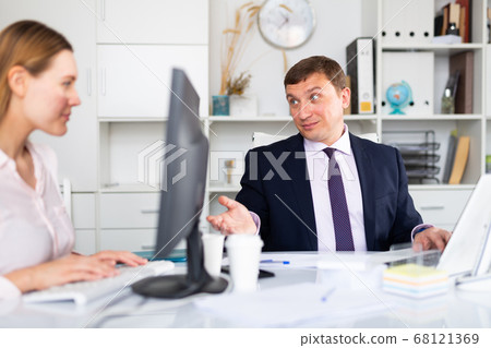 Businessman working in office with female colleague 68121369