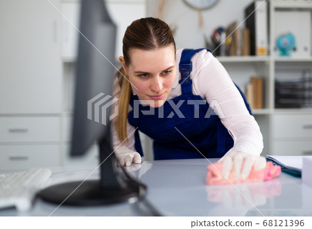 Smiling woman in uniform making cleaning in the office Smiling woman in uniform making cleaning in the office 68121396