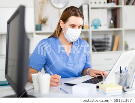 Medical worker enters patient data into laptop Medical worker enters patient data into laptop 68121397