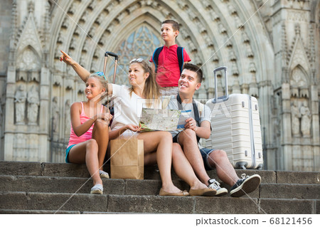 Tourist happy family of four sitting on stone with map Tourist happy family of four sitting on stone with map 68121456