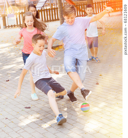Happy children playfully running after ball outdoors in park Happy children playfully running after ball outdoors in park 68121609