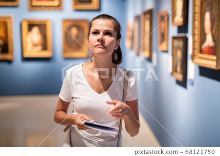 Young woman looking at artworks in museum Young woman looking at artworks in museum 68121750