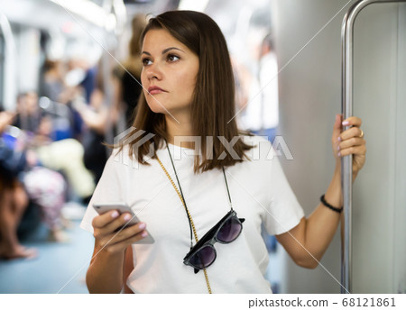 Woman using phone in subway car Woman using phone in subway car 68121861
