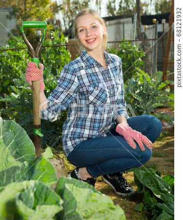 Woman hoeing in garden Woman hoeing in garden 68121932