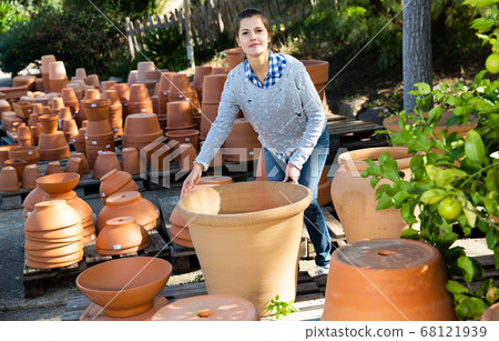 Woman chooses pots clay pots in store warehouse 68121939