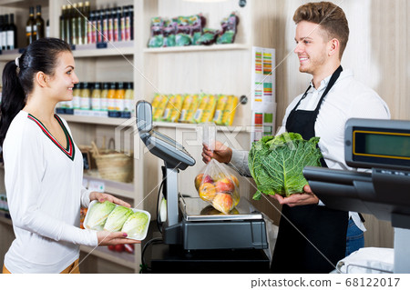 Man seller helping customer to weigh purchases Man seller helping customer to weigh purchases 68122017