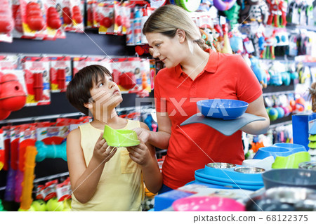 Happy teen boy with mother visiting pet shop in search of accessories for their dog Happy teen boy with mother visiting pet shop in search of accessories for their dog 68122375