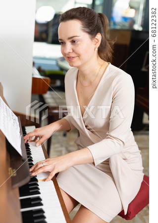 Pretty woman in evening dress playing piano Pretty woman in evening dress playing piano 68122382