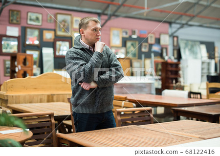 Man chooses wooden table in furniture store Man chooses wooden table in furniture store 68122416