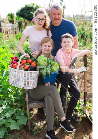 Family posing in garden with picked vegetables 68122800