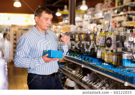 Adult male is choose fasteners and screws in tools store Adult male is choose fasteners and screws in tools store 68122855