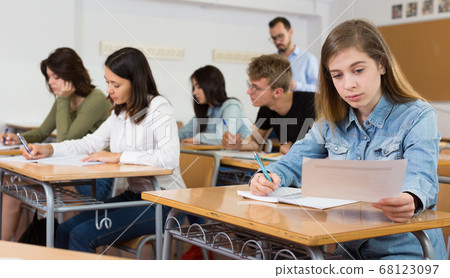 Young girl is writing test and thinking about questions at the desk Young girl is writing test and thinking about questions at the desk 68123097