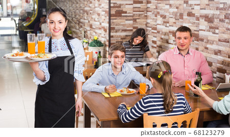 Young smiling wairtess is ready to serve salad and juice to young visitors Young smiling wairtess is ready to serve salad and juice to young visitors 68123279