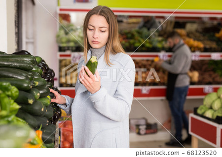 Female shopper picks cucumbers at grocery store 68123520