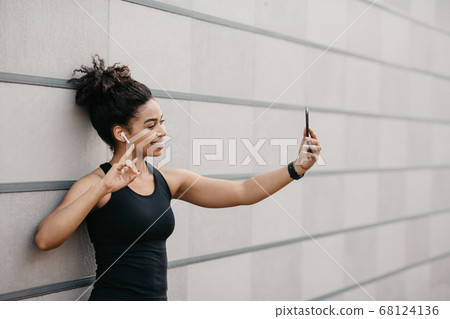 Sports blogger on street workout. Happy girl with fitness tracker makes selfie on smartphone Sports blogger on street workout. Happy girl with fitness tracker makes selfie on smartphone 68124136