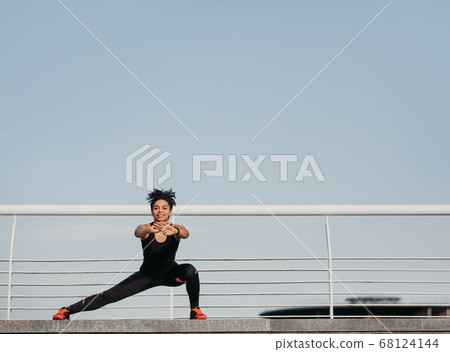 Woman exercise for good health. Happy african american young woman in sportswear with fitness tracker doing leg exercises 68124144