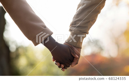 Loving afro couple holding hands while walking outdoors Loving afro couple holding hands while walking outdoors 68124335