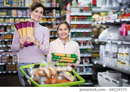 Glad woman with girl choosing delicious pasta Glad woman with girl choosing delicious pasta 68124573