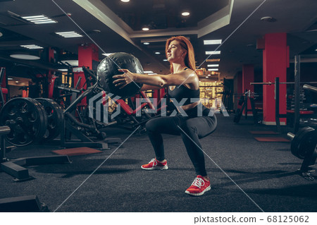 Young muscular caucasian woman practicing in gym with equipment. Wellness, healthy lifestyle, bodybuilding. 68125062
