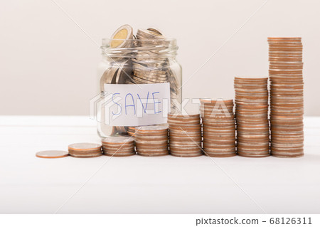 Hand of male putting coins in jar with money stack 68126311