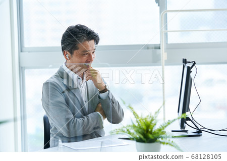 Middle businessman working in an office with an acrylic partition Middle businessman working in an office with an acrylic partition 68128105
