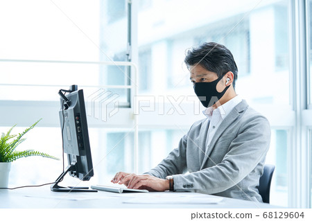 Middle businessman wearing a mask and working in the office Middle businessman wearing a mask and working in the office 68129604