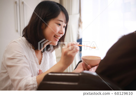 Mother giving a baby food to a baby Mother giving a baby food to a baby 68129610