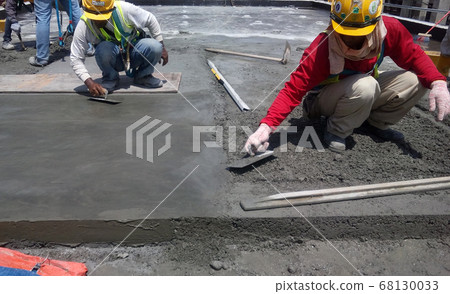 KUALA LUMPUR, MALAYSIA -SEPTEMBER 05, 2017: Construction workers leveling wet concrete has been poured. They also using long trowel for this job. KUALA LUMPUR, MALAYSIA -SEPTEMBER 05, 2017: Construction workers leveling wet concrete has been poured. They also using long trowel for this job. 68130033