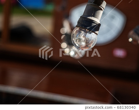 A single transparent light bulb in a black plinth on a blurred background 68130340