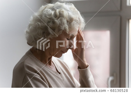 Elderly woman closed eyes touch forehead suffers from severe headache 68130528