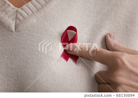 Red ribbon on breast of elderly woman closeup image 68130894