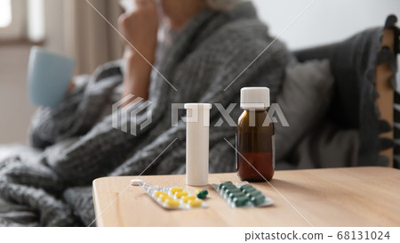 On bedside table pills sick woman holding cup on background On bedside table pills sick woman holding cup on background 68131024