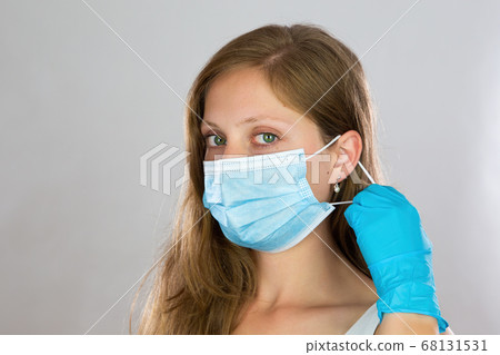 Young blonde woman putting on face mask in studio. 68131531