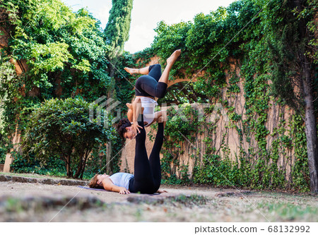 Two beautiful women doing acroyoga in the garden or park 68132992