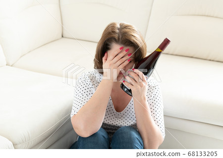 Woman with a headache and a a bottle of wine. Hangover 68133205