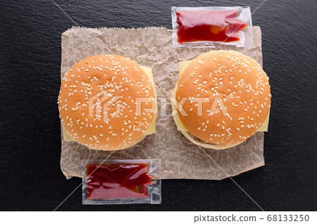 top view of two tasty homemade burgers on paper and ketchup on black background top view of two tasty homemade burgers on paper and ketchup on black background 68133250