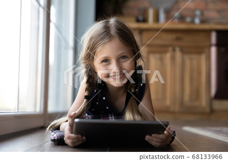 Portrait of smiling little girl using tablet on floor 68133966