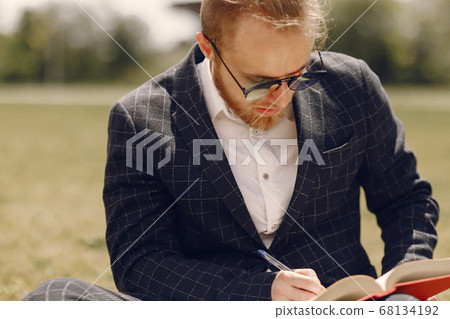 Businessman with book sitting in a summer city 68134192