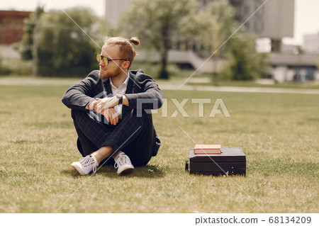 Businessman with book sitting in a summer city Businessman with book sitting in a summer city 68134209