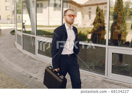 Businessman with suitcase walking in a summer city Businessman with suitcase walking in a summer city 68134227