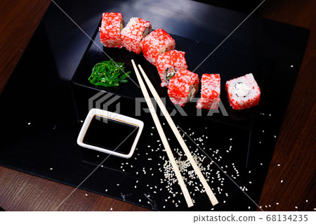 Sushi with salmon. Soy sauce, red caviar. Sushi on a black background. 68134235