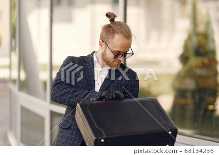 Businessman with suitcase walking in a summer city Businessman with suitcase walking in a summer city 68134236