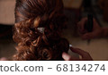Close-up of a stylist brides her hair at a wedding 68134274