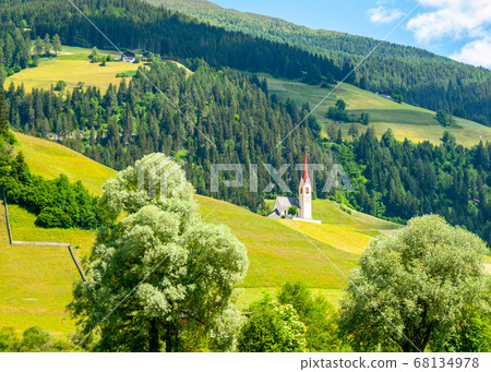 Rural church in green hilly landscape of Dolomites, Winnebach village, Italy 68134978