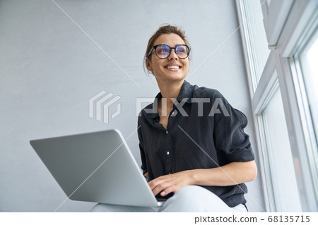 Jolly young woman using notebook for fun indoors 68135715